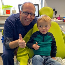 Dentist and child in dental chair giving thumbs up