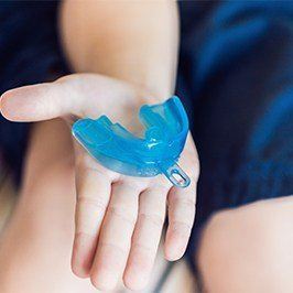 Hand holding a blue mouthguard