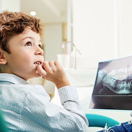 Young male dental patient discussing X-ray with dentist