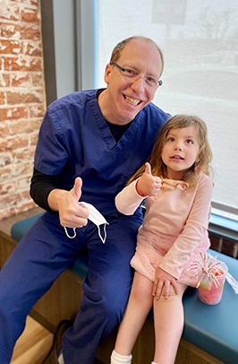 Denver pediatric dentist giving thumbs up with young girl in dental office