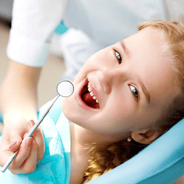 girl smiling while having her teeth checked