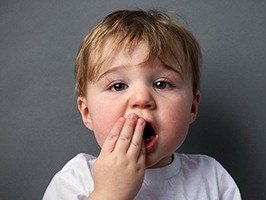 Little boy covering mouth