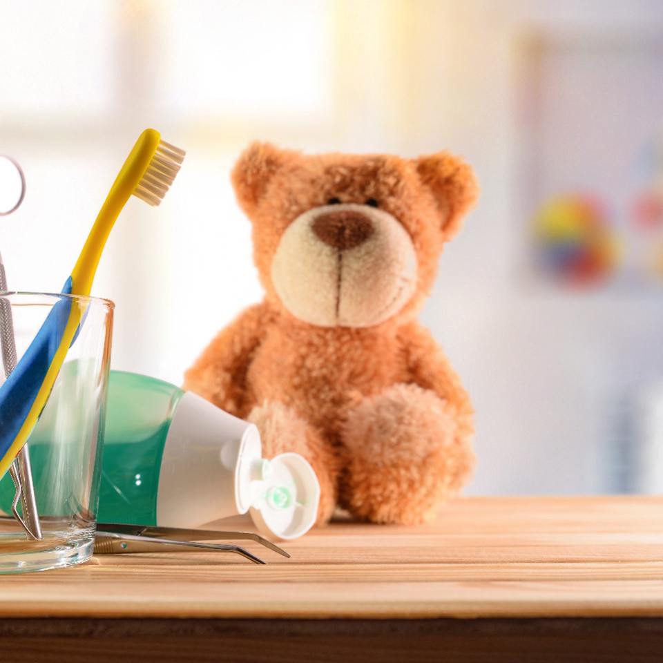 Teddy bear next to a glass with dental instruments inside for a pedo office