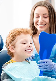 Child smiling in mirror after getting metal-free filling