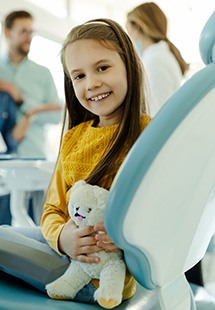 Child smiling while dentist and parents discuss dental sealants