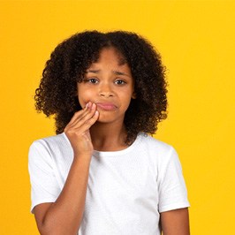 older child holding their face in dental pain