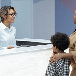 mother and child at the front desk of a dental office