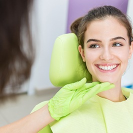 smiling teen patient with her hygienist’s hand under her face