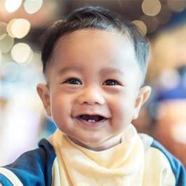 A baby boy showing off his two lower front teeth and smiling