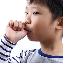 Little boy in striped shirt sucking his thumb