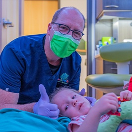 Child with hand on face experiencing a dental emergency