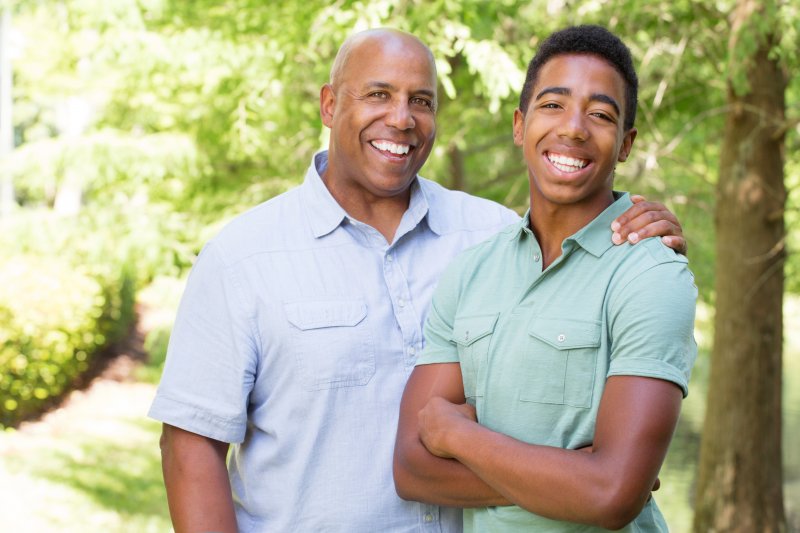 a father and son standing outside and smiling 