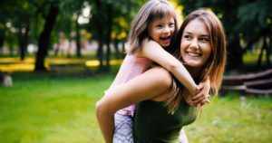 a mother and her daughter laughing and smiling while playing in the park