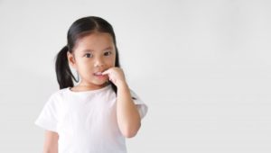 a little girl with pigtails bites her fingernails