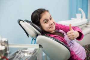 girl using her children’s dental insurance coverage and giving a thumbs up