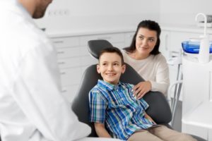 parent helping their child at the dentist’s after tooth extraction