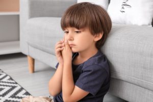 little boy holding his face in dental pain