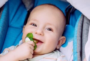 smiling baby with a pacifier in their mouth