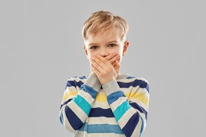 Young boy covering his mouth